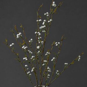 Close up of Glimpse Homes classic white long stem artificial wildflower branches arranged in a white fluted vase against a dark background.