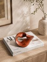 Premium wooden knot decor styled on a stack of Architectural Digest magazines on a wooden cabinet, showcasing The Trinity Knot by Glimpse Homes as a sophisticated interior accent.