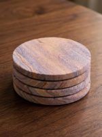 A tidy stack of four Glimpse Homes eco-friendly sandstone coasters on a wooden surface, showcasing their smooth 1 cm thick edges.