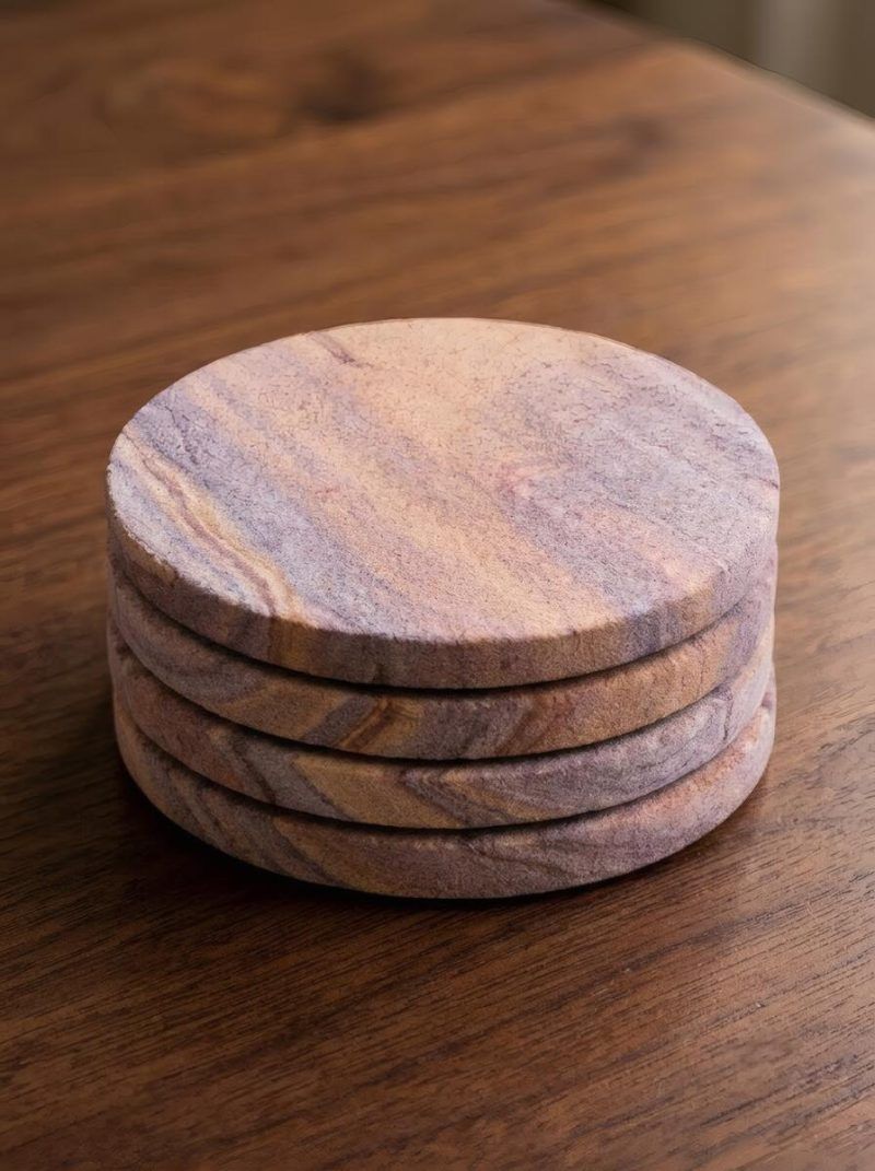 A tidy stack of four Glimpse Homes eco-friendly sandstone coasters on a wooden surface, showcasing their smooth 1 cm thick edges.