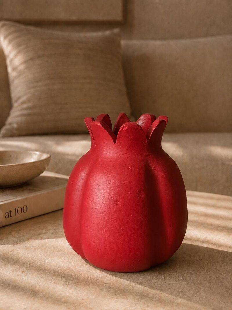A large 7.5-inch ravishing red handmade terracotta pomegranate showpiece by Glimpse Homes, styled as an elegant center table decor in a living room.