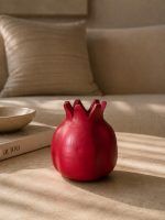 A ravishing red handmade terracotta pomegranate showpiece by Glimpse Homes, styled on a modern coffee table in a cozy living room setting.