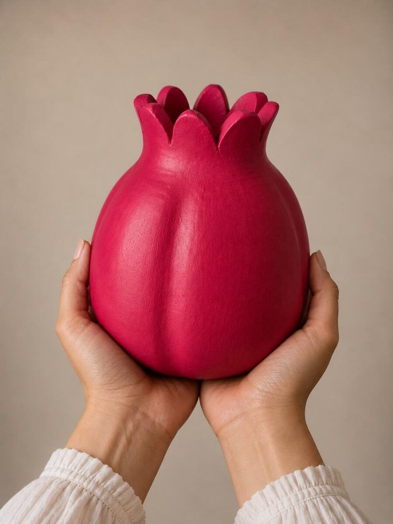Two hands holding the large 7.5-inch ravishing red handmade terracotta pomegranate showpiece by Glimpse Homes, highlighting its substantial artisanal scale.