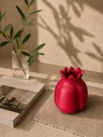 Large handmade terracotta pomegranate showpiece in a ravishing red finish, set on a woven mat as aesthetic table decor alongside a Glimpse Homes book.