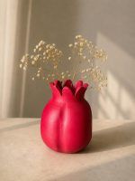 The large 7.5-inch ravishing red terracotta pomegranate showpiece styled creatively as a rustic vase with dry baby's breath flowers on a sunlit table.