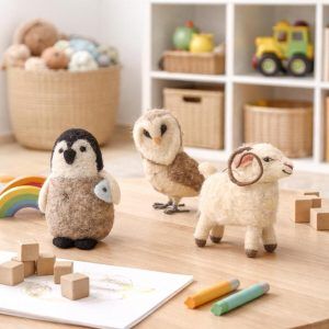 Set of three Glimpse Homes felt animals sitting on a wooden playroom table surrounded by crayons and wooden blocks.