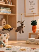 Felt tortoise, rabbit and carrot ornaments strung above a cozy kids playroom shelf