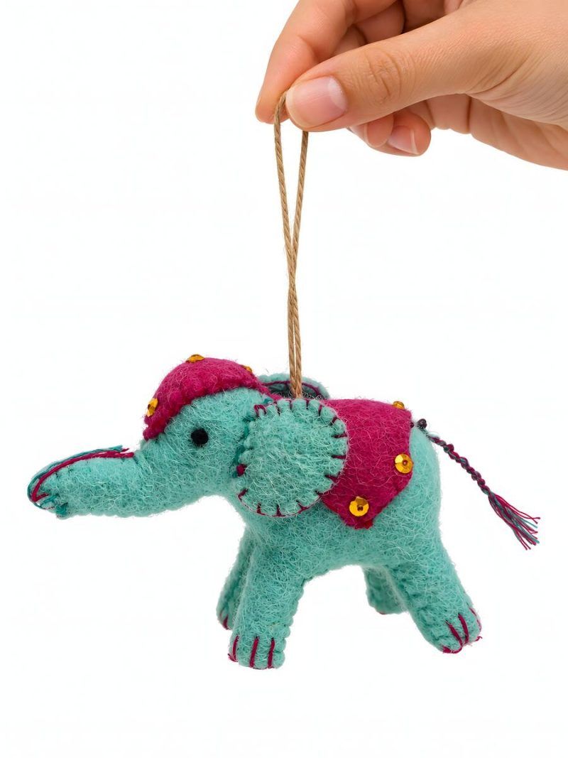 Hand holding a turquoise felt elephant nursery ornament by Glimpse Homes