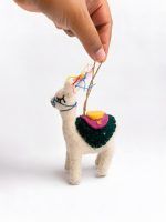 Hand holding a Glimpse Homes felt llama ornament showing colorful saddle and tassel detailing