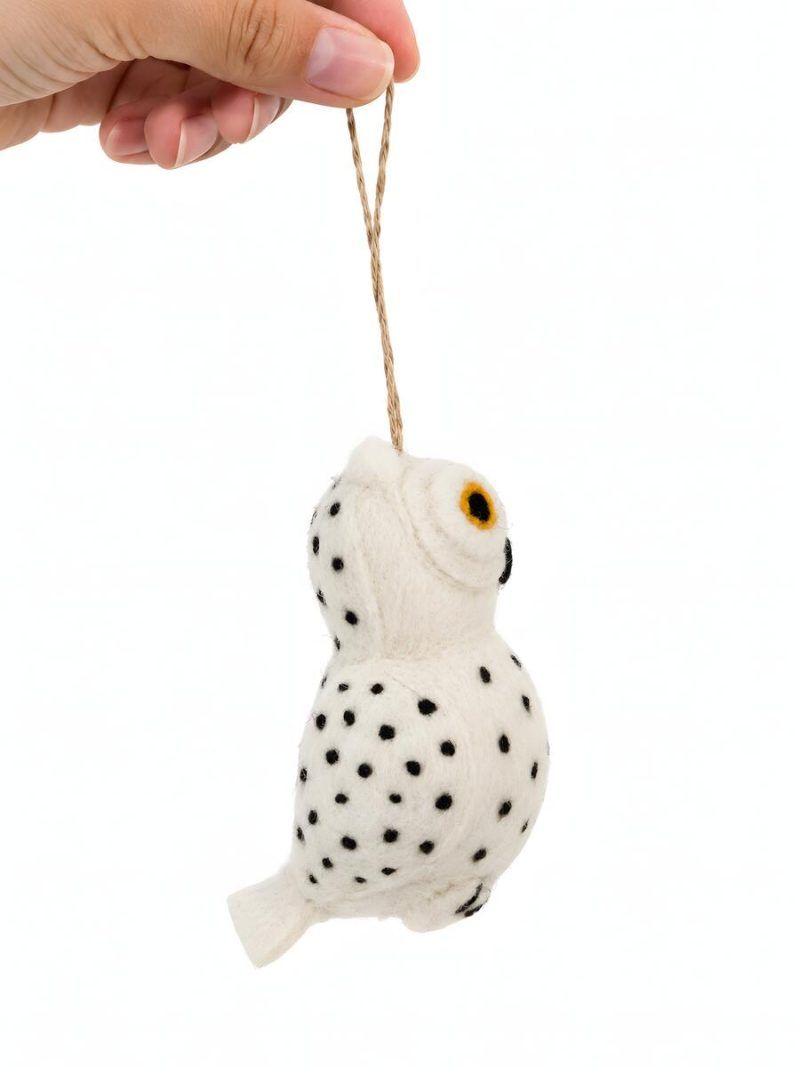 Hand holding a Glimpse Homes felt owl ornament showing spotted wings and hanging string