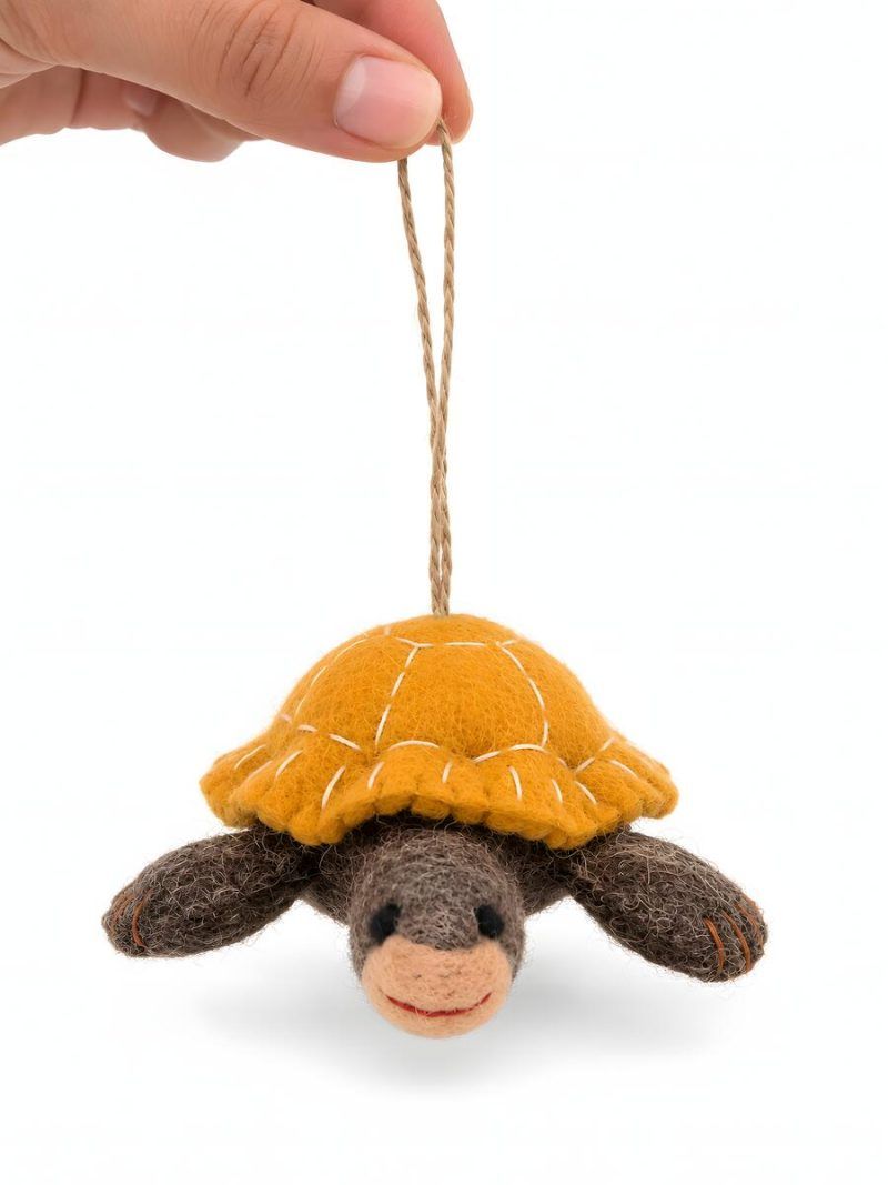 Hand holding a felt tortoise ornament with mustard yellow shell, front view