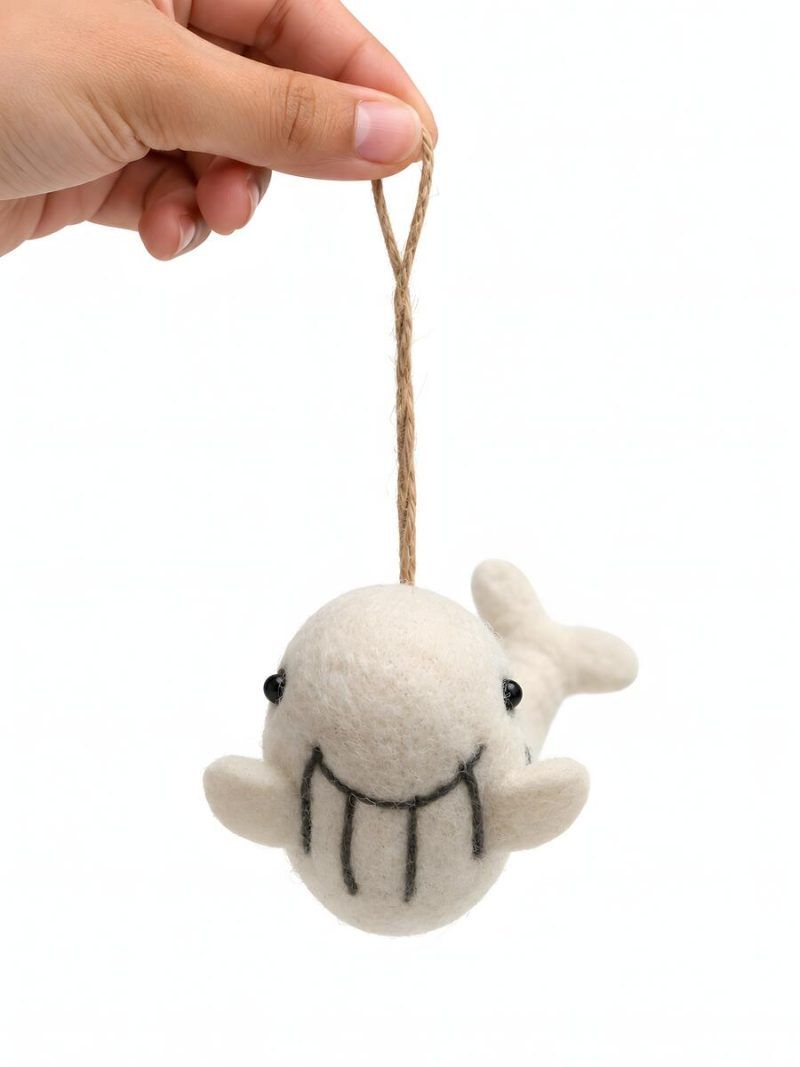 Front view of felt whale nursery ornament with smiling embroidered face by Glimpse Homes