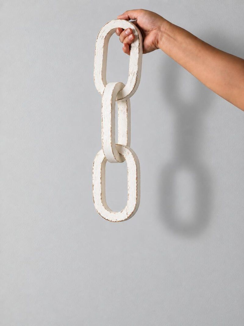 Hand holding 3 Knot Long Wooden Chain Sculpture in Vintage White Finish - Glimpse Homes decorative accent.