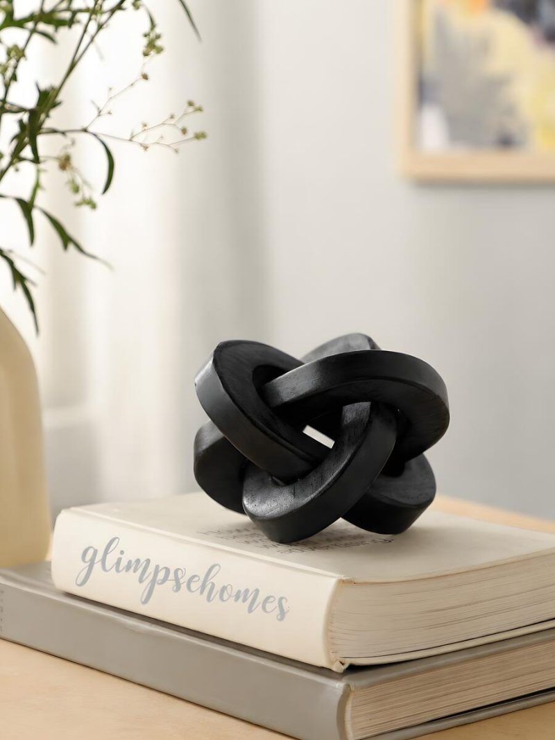 Glimpse Homes black wooden triple knot ornament displayed on bookshelf with home decor accents.
