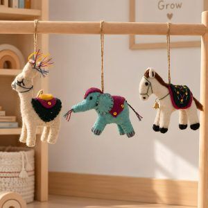 Glimpse Homes felt llama, elephant and horse ornaments hanging on a wooden mobile in a kids' nursery room