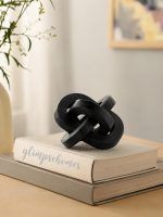 Black wooden triple knot sculpture by Glimpse Homes styled on stacked books for home decor.