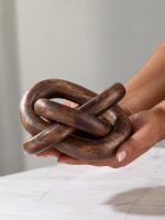 Close-up of hand-carved Glimpse Homes 3 knot wooden chain decor piece in rich walnut finish