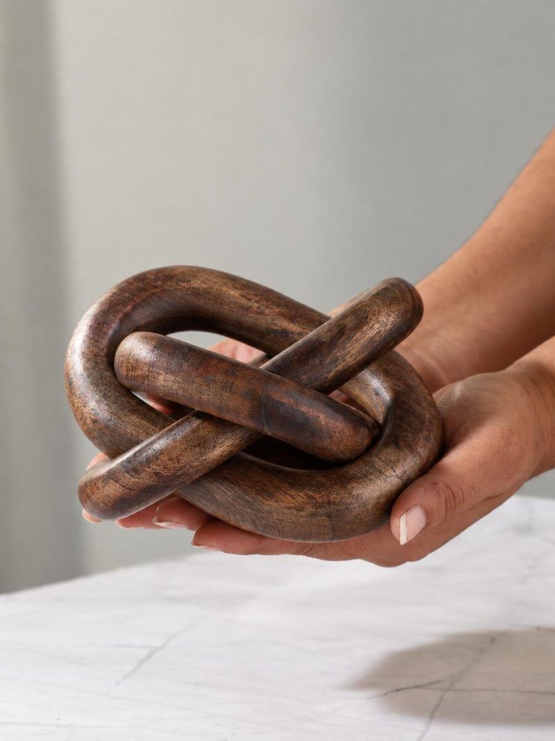 Close-up of hand-carved Glimpse Homes 3 knot wooden chain decor piece in rich walnut finish