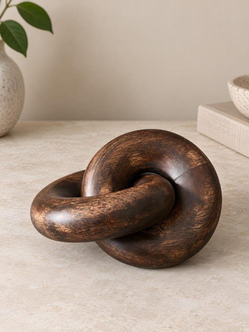 Close-up of Glimpse Homes walnut finish wooden knot chain decor showing rich wood grain texture.