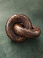 Detailed view of handcrafted walnut wood knot chain link on textured green backdrop.