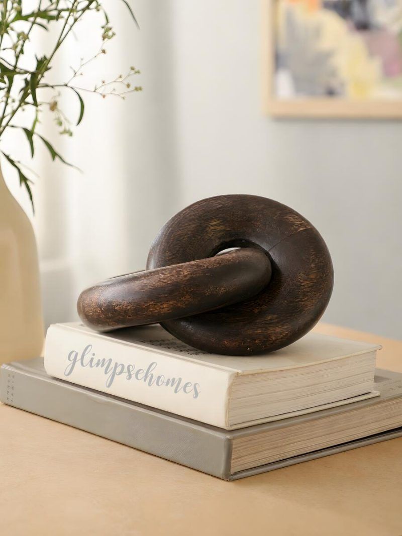 Glimpse Homes walnut finish wooden knot chain decor piece displayed on stacked books.